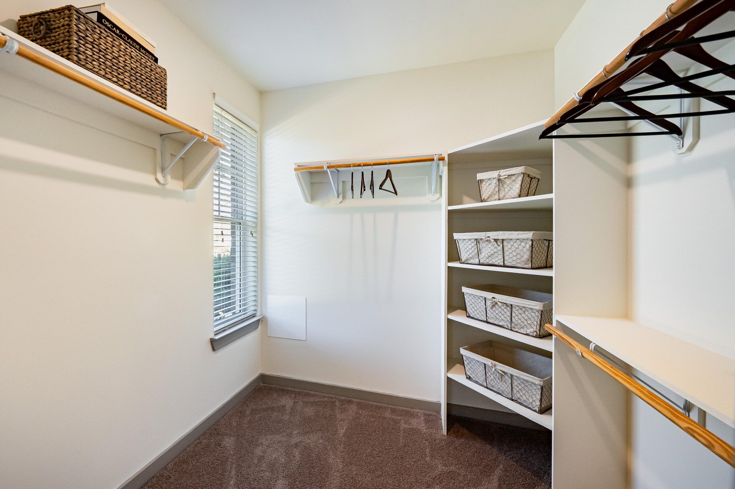 Spacious walk-in closet with shelves, hanging rods, baskets, and a window letting in natural light.
