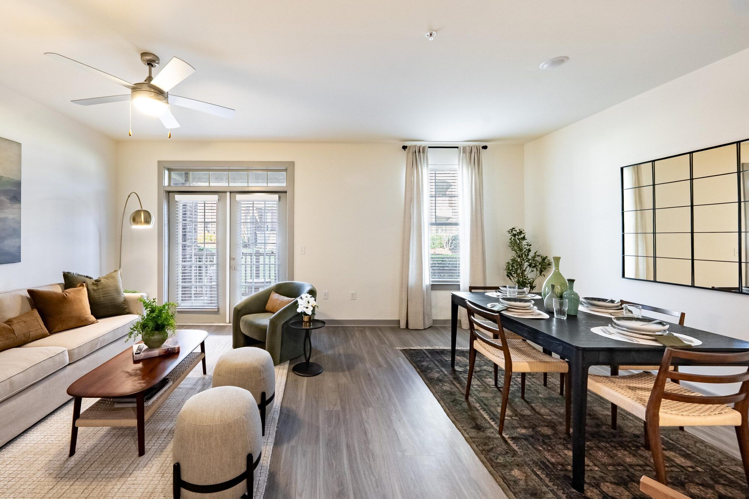 Modern living and dining area with neutral tones, wooden furniture, and large windows letting in natural light.