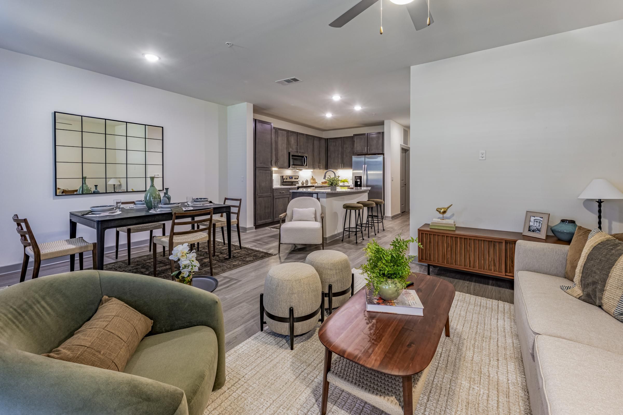 Modern open-plan living room and kitchen with neutral decor, cozy seating, and a dining area.